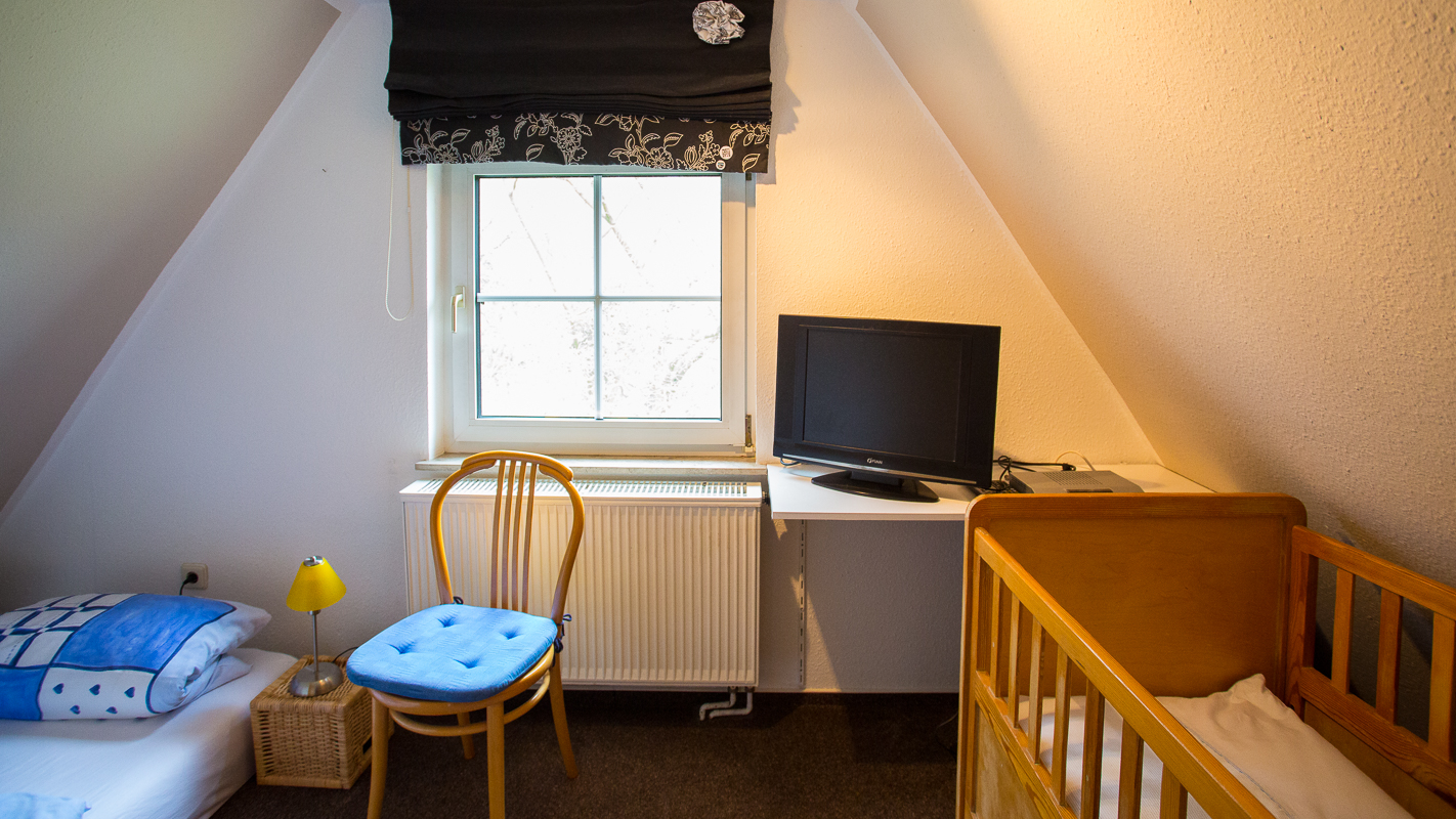 Zimmer mit Doppelbett, Fernseher und Kinderbett